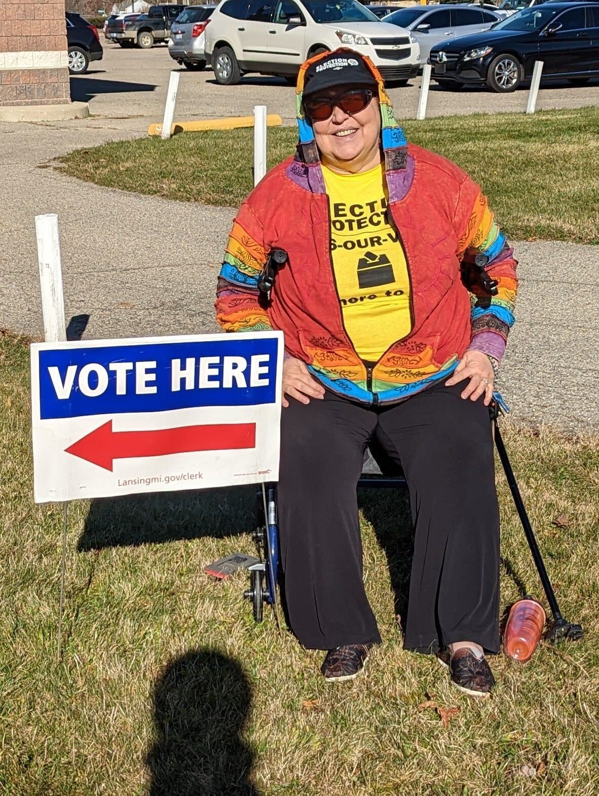 Image of a disabled election protection volunteer sitting next to a 